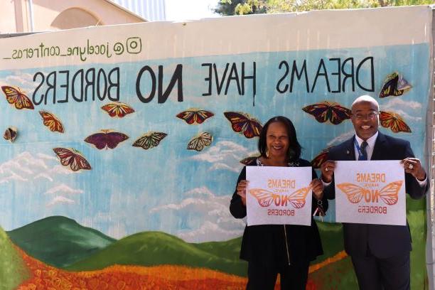 Student service staff members posing in front of the mural.